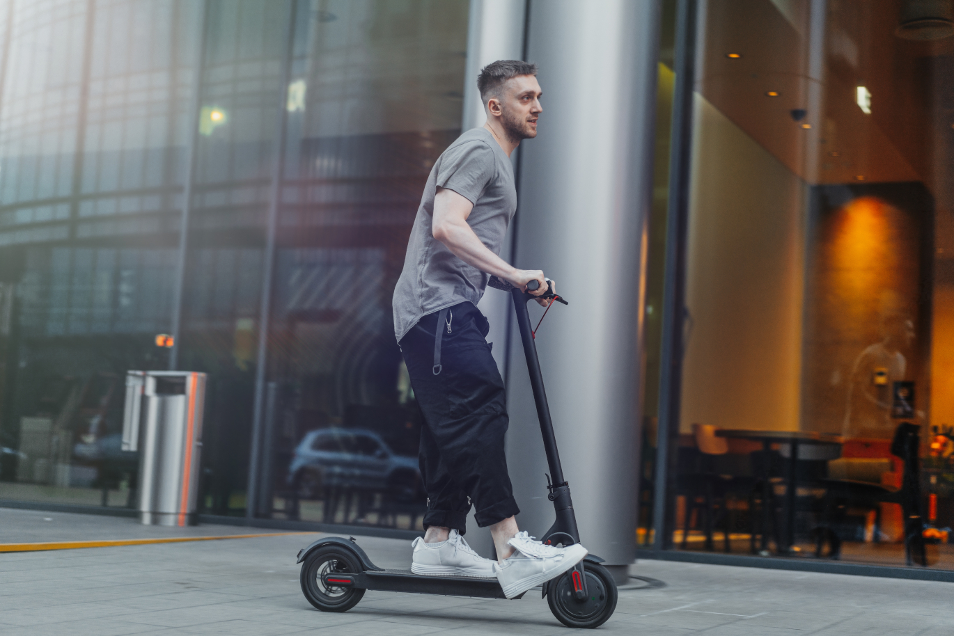 attractive man riding a kick scooter at cityscape background. Elektroroller