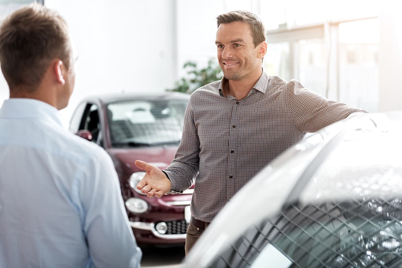 visitor demonstrating happiness while speaking with agent in car dealership Autokauf